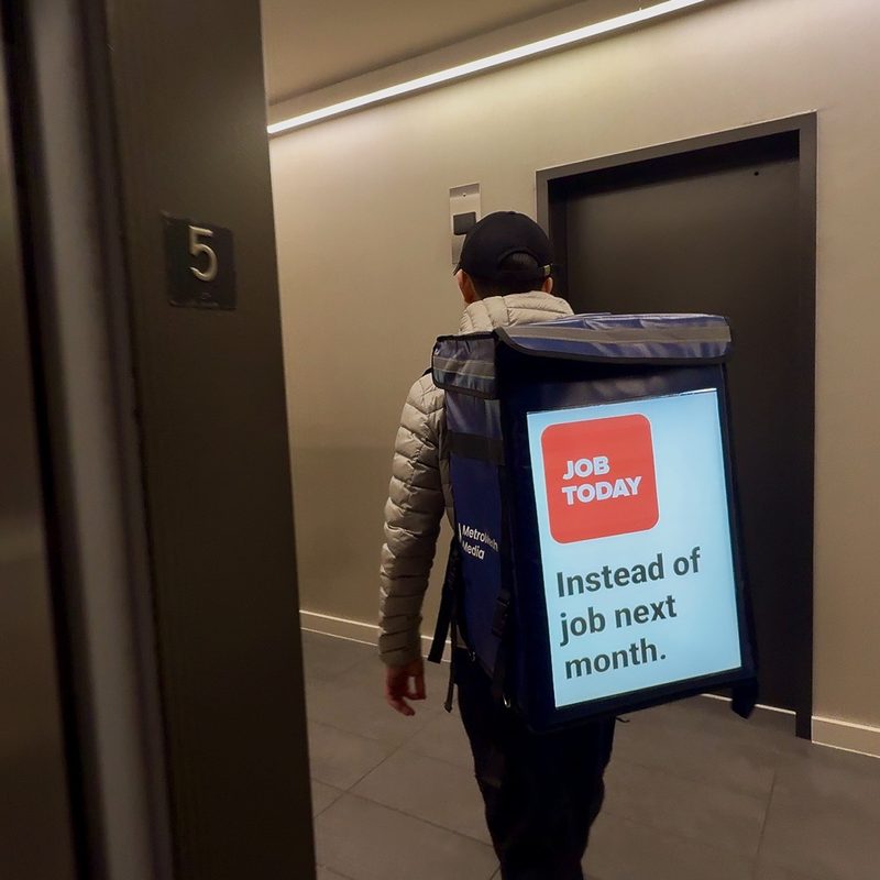 Rider carrying a lit MetroMesh display bag down a residential hallway